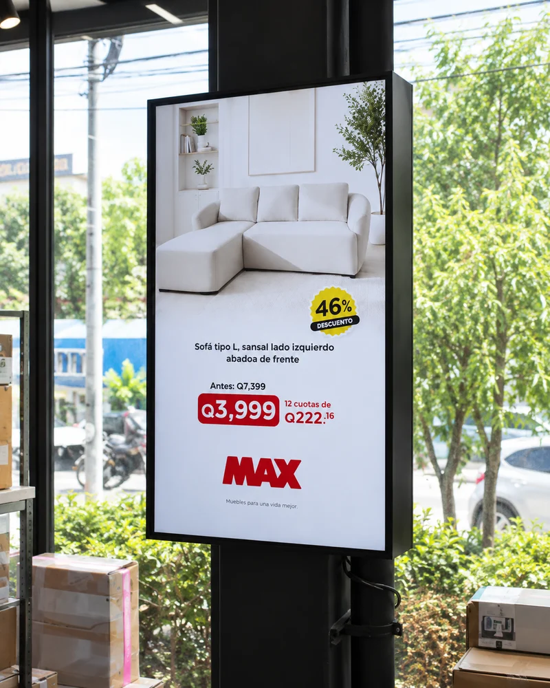 Una pantalla junto al ventanal de una tienda MAX muestra una promoción de muebles.